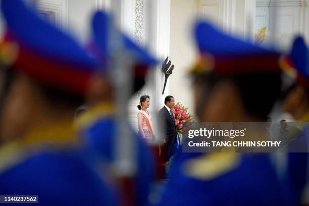 Myanmar's State Counsellor Aung San Suu Kyi and Cambodia's Prime Minister Hun Sen listen to their national anthems during her visit at the Peace...