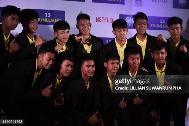 Members of the 'Wild Boars' football team pose for a photo with their coach Ekkapol Chantawong during a press conference in Bangkok on April 30, 2019...