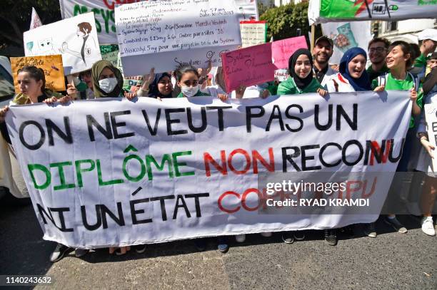 Algerian students hold a banner and placards on April 30, 2019 as they continue their weekly protests in the capital Algiers to demand the overthrow...