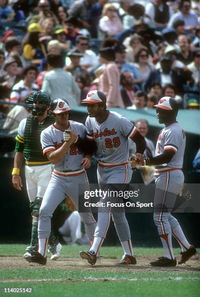 Ken Singleton of the Baltimore Orioles after hitting a home run against the Oakland Athletics is met by teammates Rich Dauer and Al Bumbry during a...