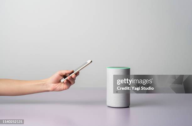 woman using a smart speaker with smart phone. - ai speaker stock-fotos und bilder