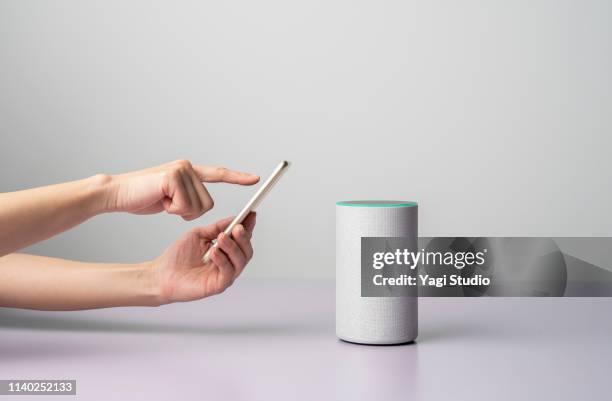 woman using a smart speaker with smart phone. - wifi stockfoto's en -beelden