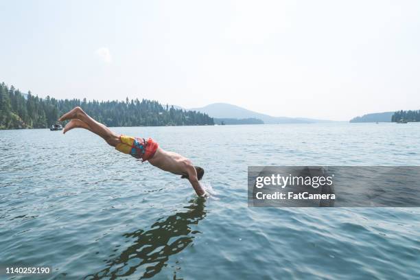 young man dives into a pristine lake - 2017 usa diving summer stock pictures, royalty-free photos & images