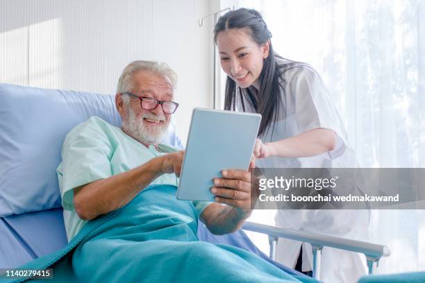 nursing by the elderly male patient bed in the hospital - nurse with old male patient home care stock-fotos und bilder