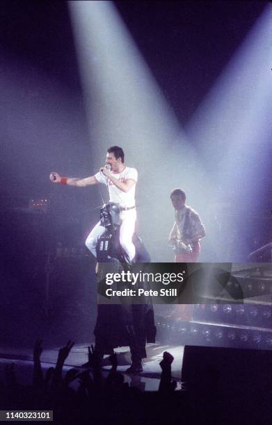 Freddie Mercury of Queen wears a Flash Gordon T-shirt and salutes the crowd while on the shoulders of 'Darth Vader' during a performance on stage at...