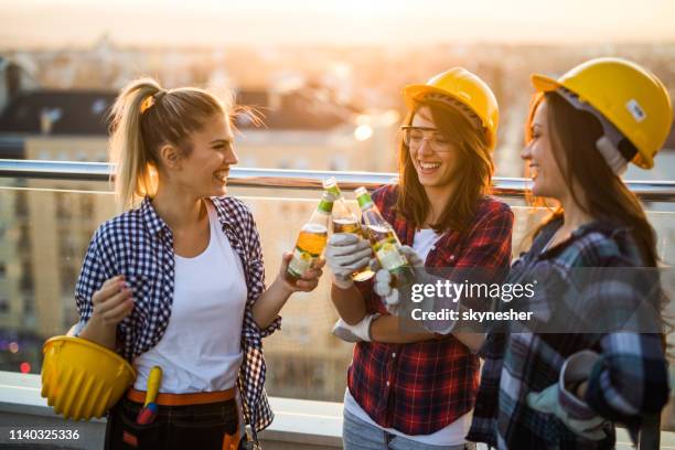 team of happy construction workers toasting with beer on a terrace. - beer helmet stock pictures, royalty-free photos & images