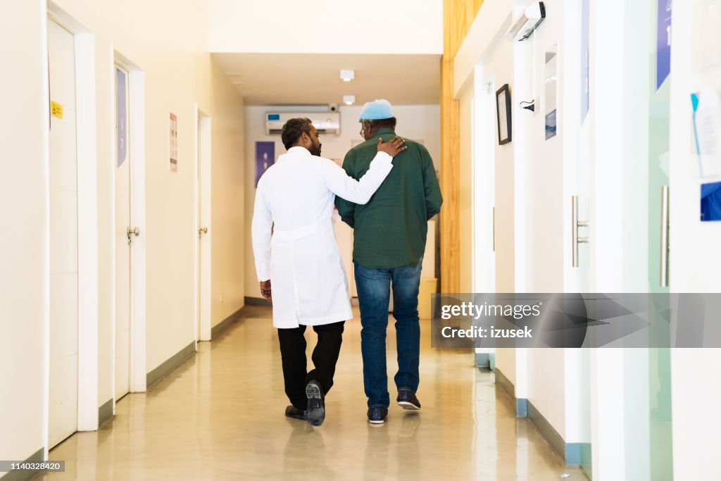 Rückansicht des Arztes mit Patient im Flur
