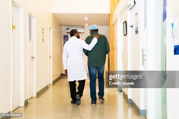 rückansicht des arztes mit patient im flur - doctors walking stock-fotos und bilder