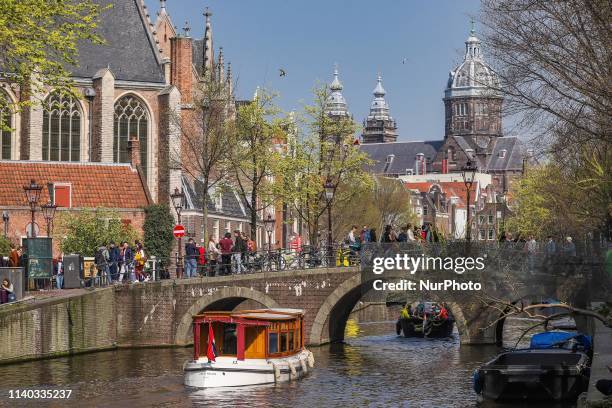 Boats and vessels inside the canals of Amsterdam in The Netherlands, with traditional houses and bridges over the water. The little ships are used...