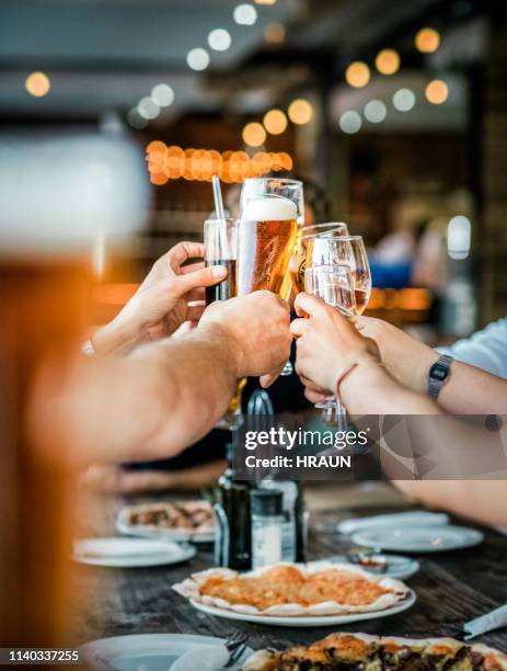 friends toasting drinks at party in restaurant - beer on table stock pictures, royalty-free photos & images