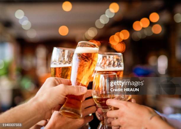 mains d’amis élevant le toast de célébration au bar - bière photos et images de collection