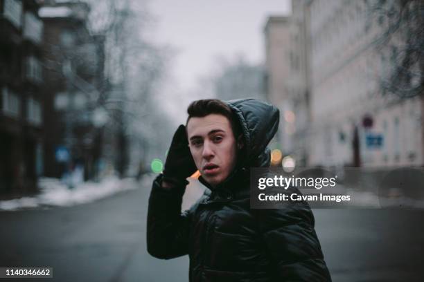 young man crossing road in city during winter - pedestrian winter stock pictures, royalty-free photos & images