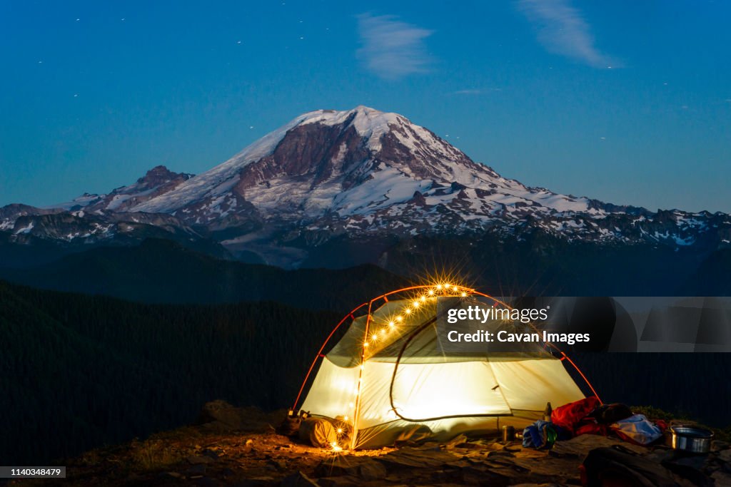 Night view of backpacking tent with string lights and Mt Rainier