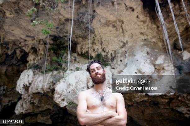 man outside a cave with arms crossed - brusthaar stock-fotos und bilder