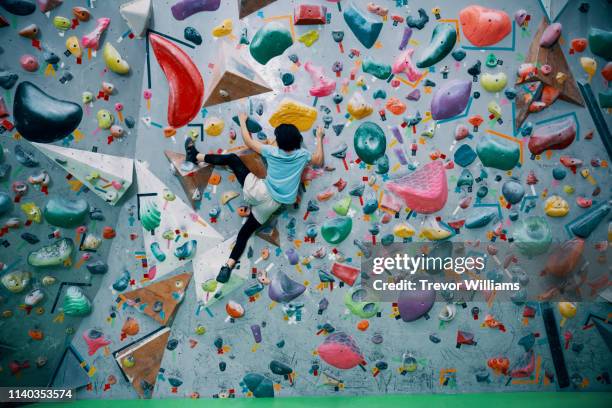 one teenage girl climbing a bouldering wall at a rock climbing gym - klettern stock-fotos und bilder