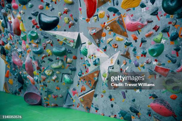 bouldering wall at a rock climbing gym - kletterwand kletterausrüstung stock-fotos und bilder