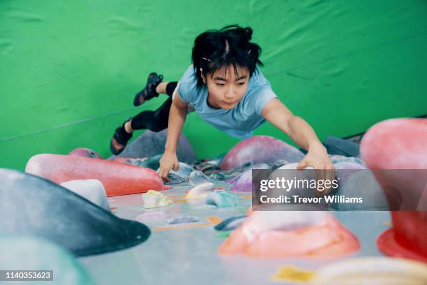 one teenage girl climbing a bouldering wall at a rock climbing gym - freiklettern stock-fotos und bilder