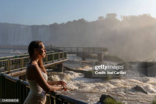 mujer escuchando el rugido de las cataratas de iguazú - garganta del diablo fotografías e imágenes de stock