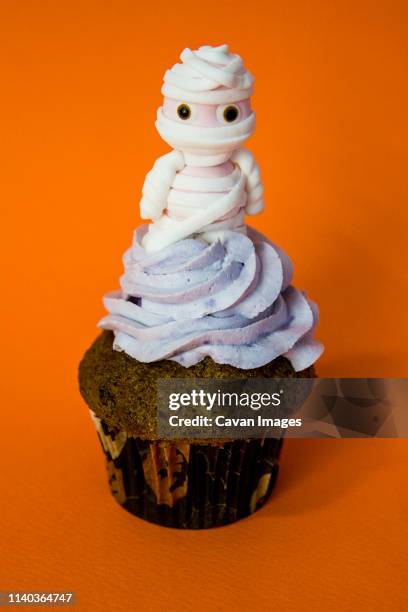 blueberry butter cream funny mummy cupcake with orange background - yummy mummy stockfoto's en -beelden