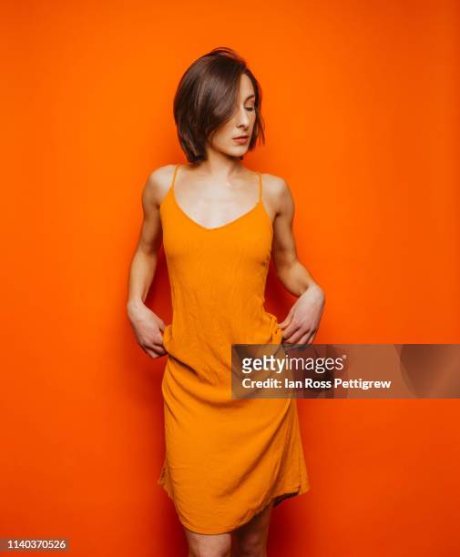 woman in orange dress on orange background - fashion orange colour stock pictures, royalty-free photos & images