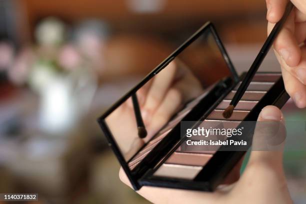 close up of woman brushing with eye shadow pallet - eyeshadow foto e immagini stock