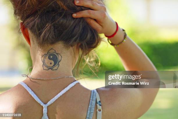 young woman back view showing tatoo - tattoo shoulder stock-fotos und bilder