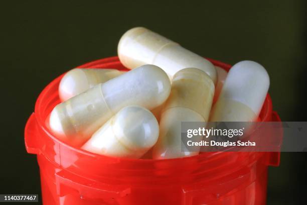 overflowing capsules from a red pill bottle - probiotic stock pictures, royalty-free photos & images