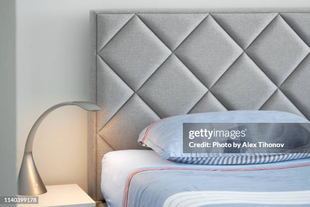 minimalistic empty bedroom design interior indoors, silver color lamp turned on in bedside table, part of bed, no people - alex grey stock-fotos und bilder