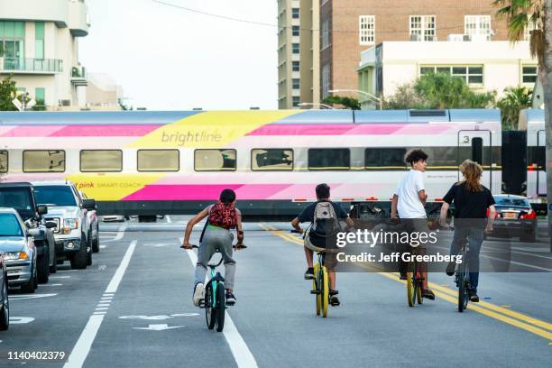 West Palm Beach, Teens biking near Brightline Passenger Train.