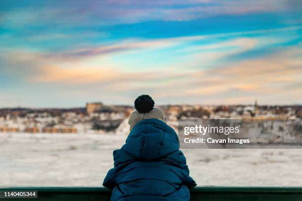 6 years old boy in winter clothes watching the sunset over the river - toque stock pictures, royalty-free photos & images