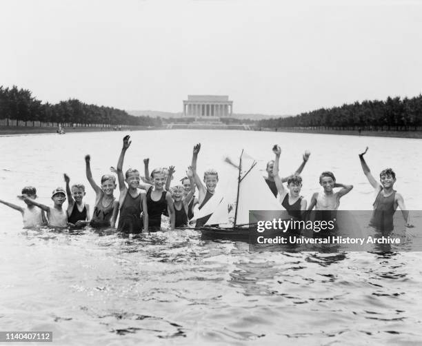 Group of Boys Waving at Camera while Playing with a Toy Sailboat in Reflecting Pool in front of Lincoln Memorial, Washington DC, July 7, 1926 .