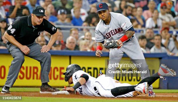 The Miami Marlins' Miguel Rojas slides safely into third base as Cleveland Indians infielder Jose Ramirez looks on in the second inning at Marlins...