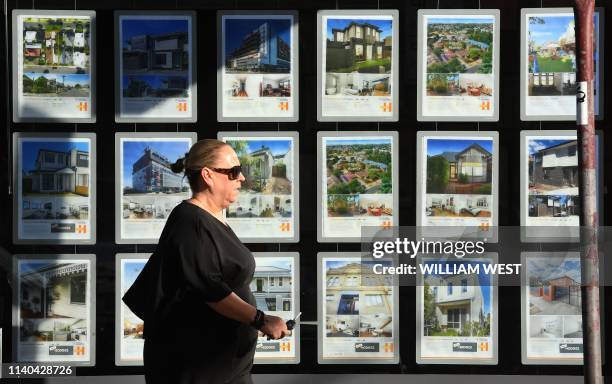 Woman walks past a real estate agent's window advertising houses for sale and auction in Melbourne on May 1, 2019. - Australian property prices fell...