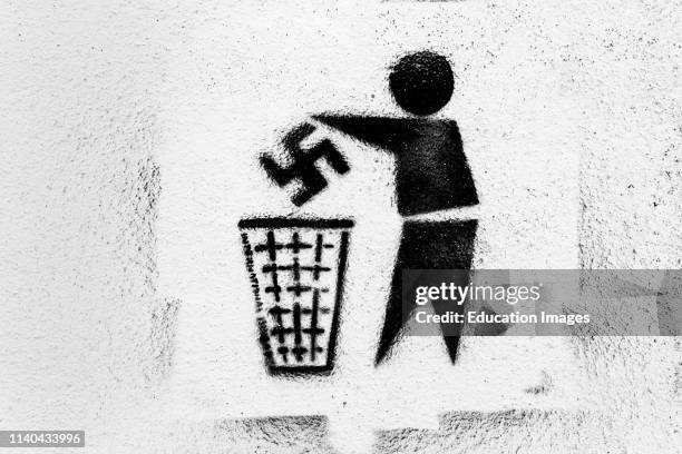 Anti-Nazi graffiti. Swastika being thrown into rubbish bin. Photographed in Tarifa, Spain.