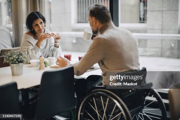 businesswoman having breakfast with businessman at table in restaurant - wheelchair restaurant fotografías e imágenes de stock