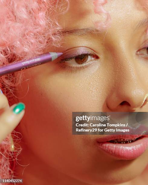 portrait of young confident woman applying eyeliner - eyeliner ストックフォトと画像