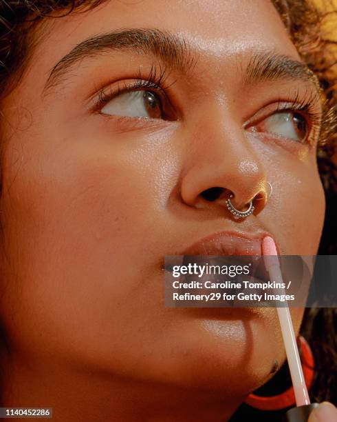 portrait of a young confident woman applying lipgloss - gloss stockfoto's en -beelden