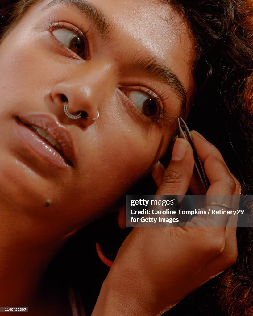 Portrait of a Young Confident Woman Plucking her Eyebrows