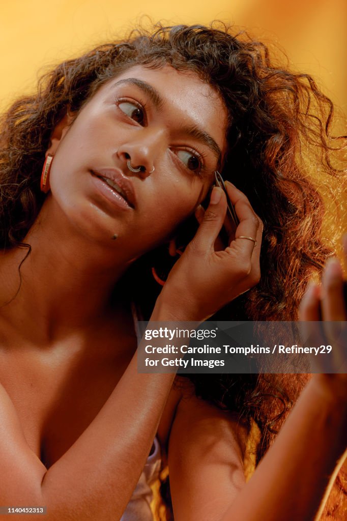 Portrait of a Young Confident Woman Plucking her Eyebrows
