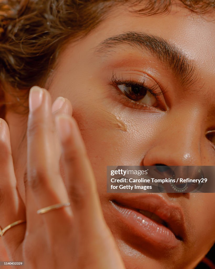 Closeup of a Young Confident Woman Applying Foundation