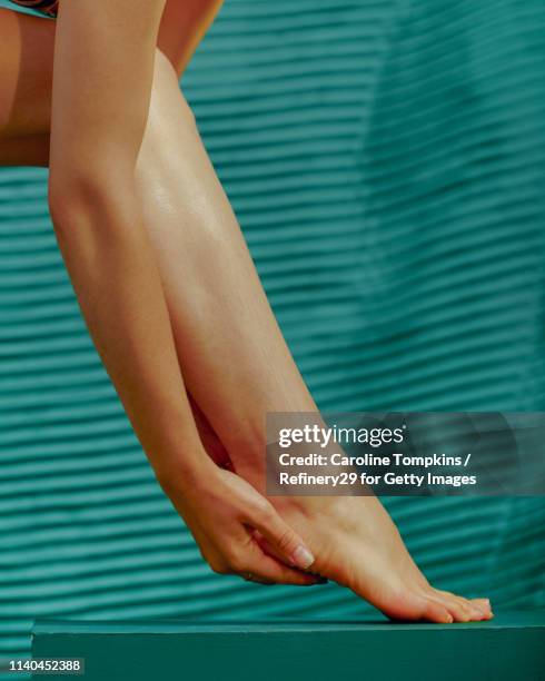 young woman putting lotion on her legs - woman legs stockfoto's en -beelden