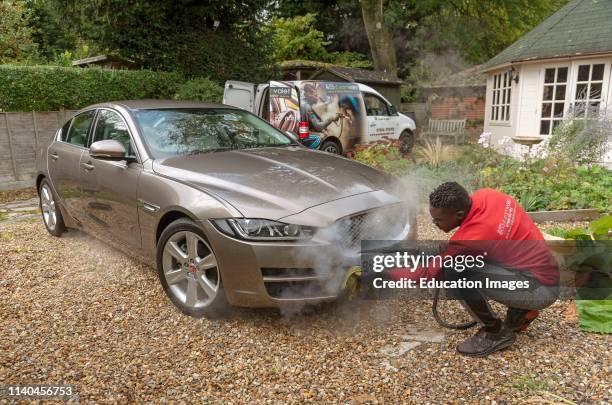 Man steam cleaning a luxury car on a home visiting valet service, England UK.