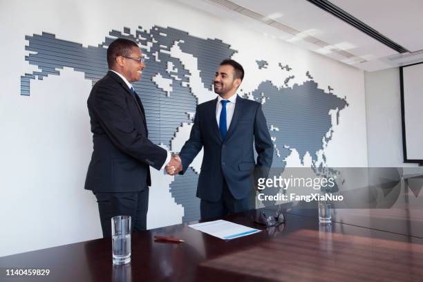 businessmen shaking hands at conference table - to assemble world stock pictures, royalty-free photos & images