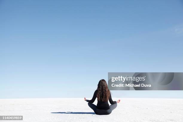 woman meditation pose facing camera on salt flat - new age concept photos et images de collection