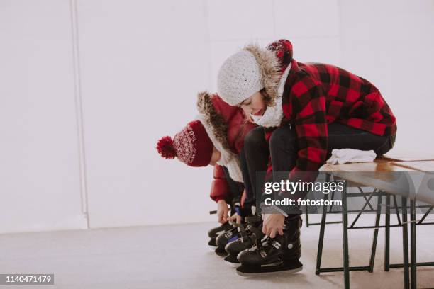 skaters putting on ice skates at rink - ice skate indoor stock pictures, royalty-free photos & images