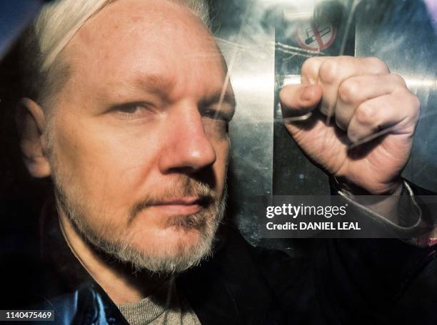 WikiLeaks founder Julian Assange gestures from the window of a prison van as he is driven into Southwark Crown Court in London on May 1 before being...