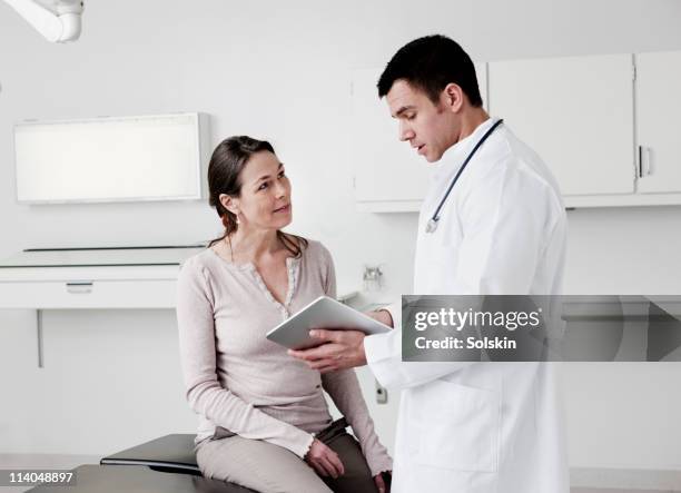 doctor using tablet computer with patient - dokter stockfoto's en -beelden