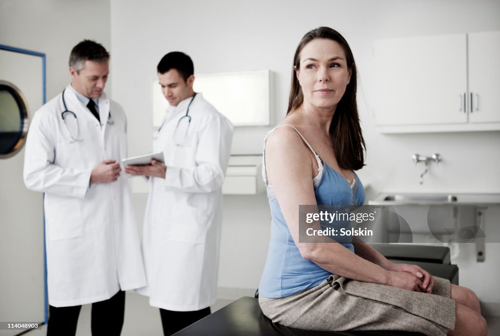 Doctors looking at tablet, patient in foreground