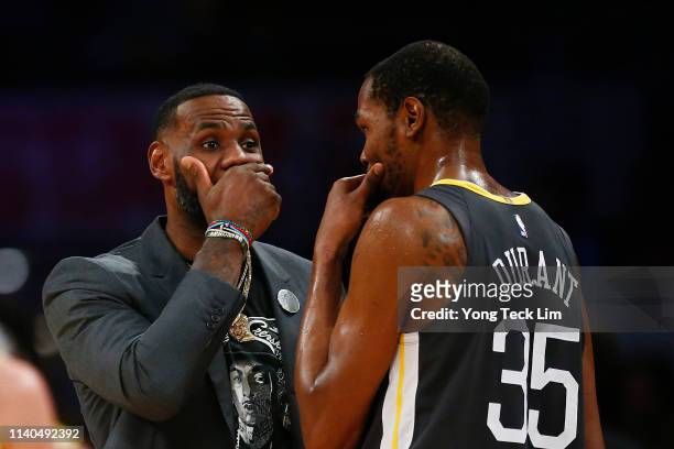 LeBron James of the Los Angeles Lakers speaks to Kevin Durant of the Golden State Warriors during a timeout in the first half at Staples Center on...