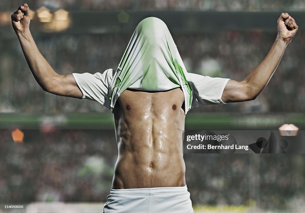 Soccer player football shirt over head, celebratin